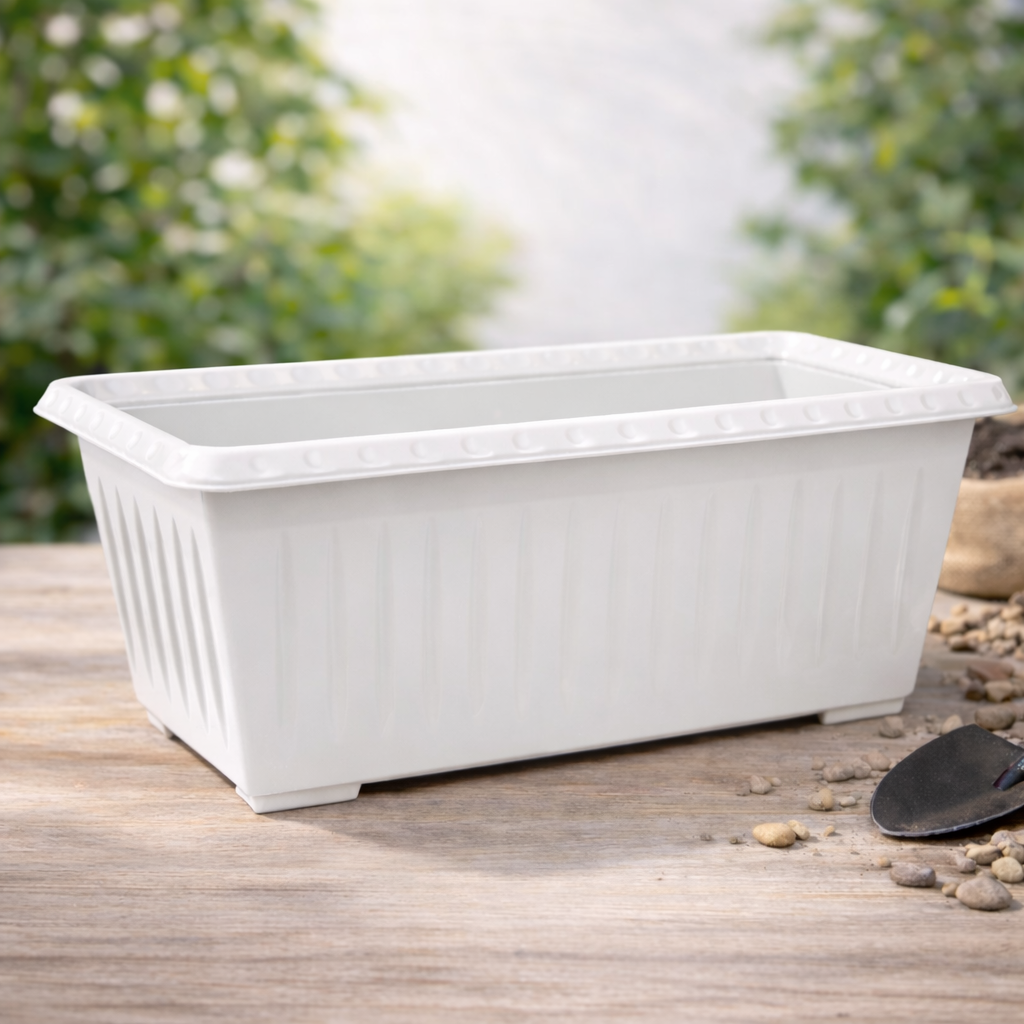 White rectangular planter on a wooden surface with a blurred green outdoor background