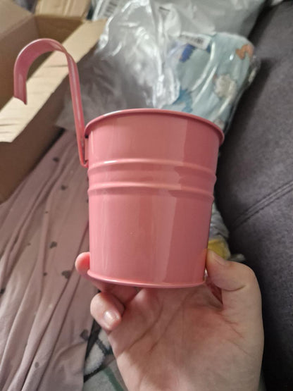 Hand holding a pink pot with a blurred background